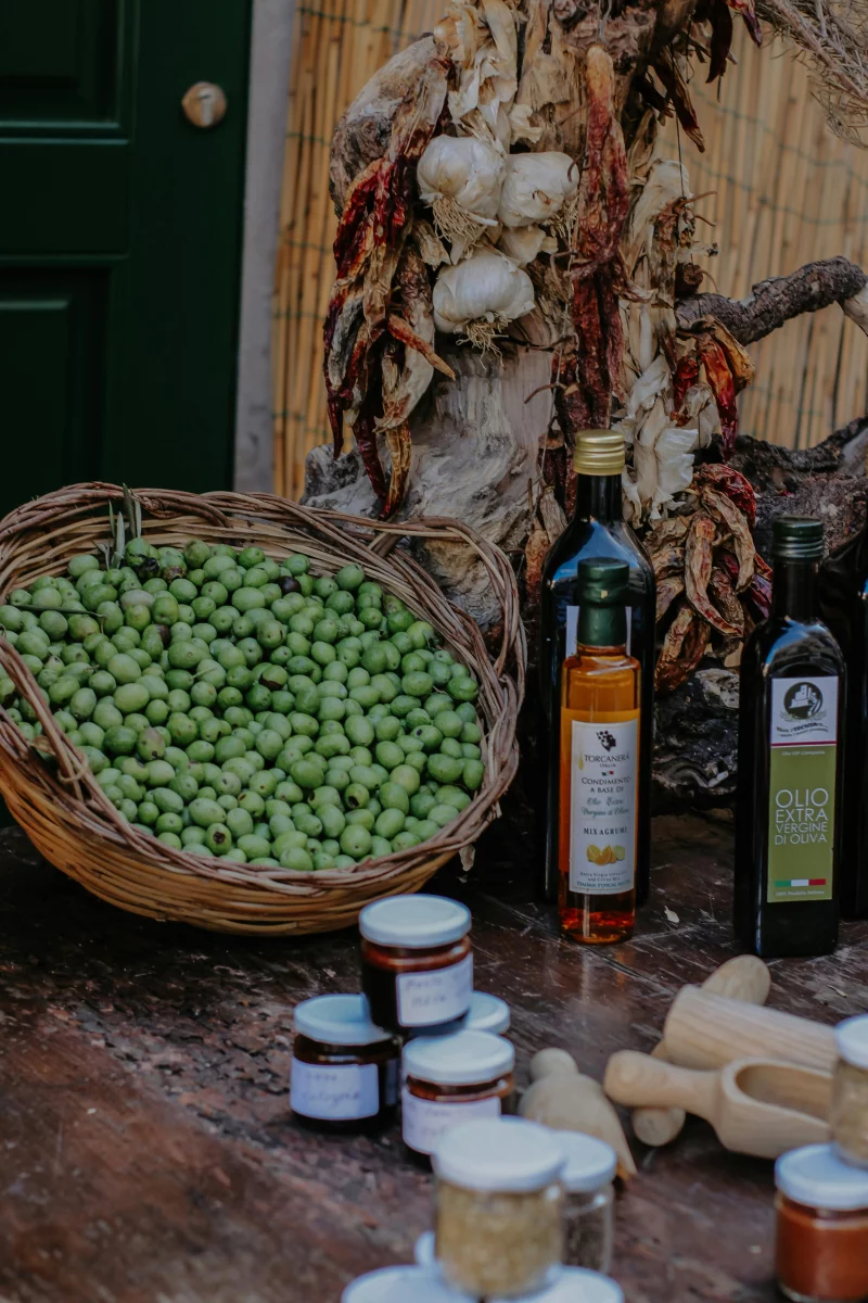 A rustic market setup with green olives, olive oil bottles, and garlic. Perfect for food themes.