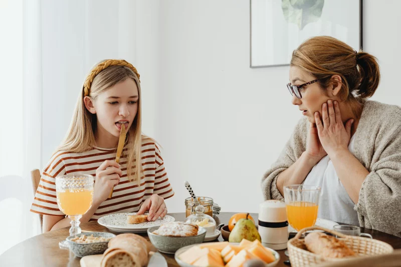 A mother and daughter enjoying a cozy breakfast together at home, featuring a variety of healthy foods.