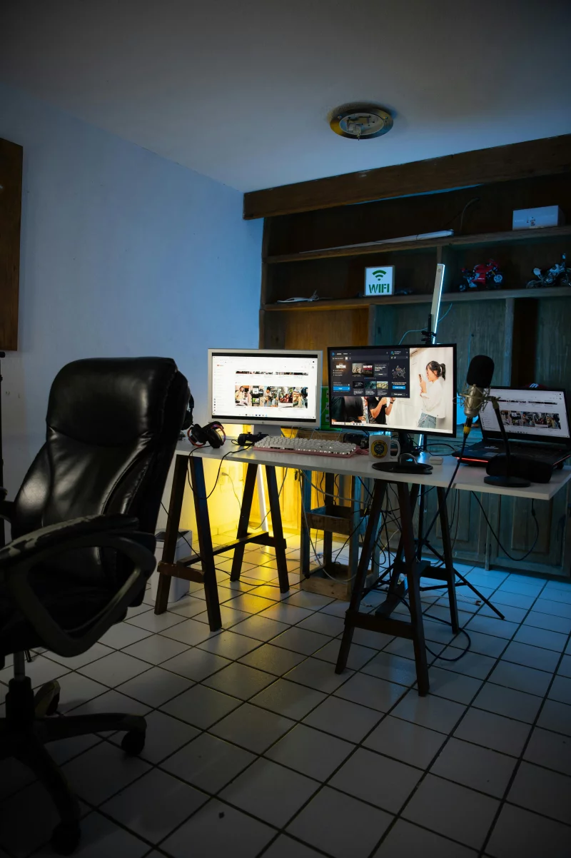 Contemporary home office setup with dual monitors, keyboard, and microphone on stylish table.