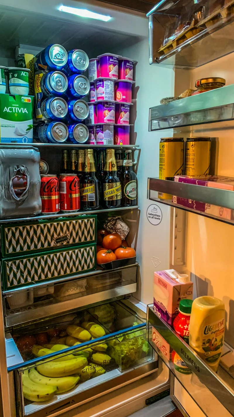 Open refrigerator filled with drinks, fruits, and dairy products, well-organized.