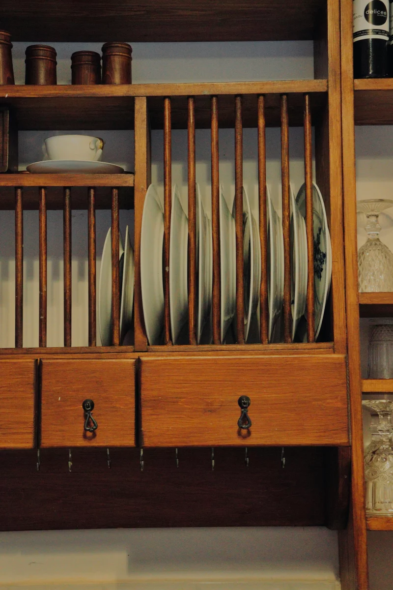 A cozy wooden kitchen plate rack with neatly arranged dishes and cups, perfect for rustic interiors.
