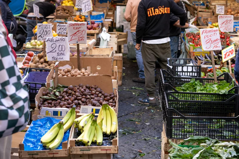 Colorful display of fruits and vegetables at a bustling outdoor market.