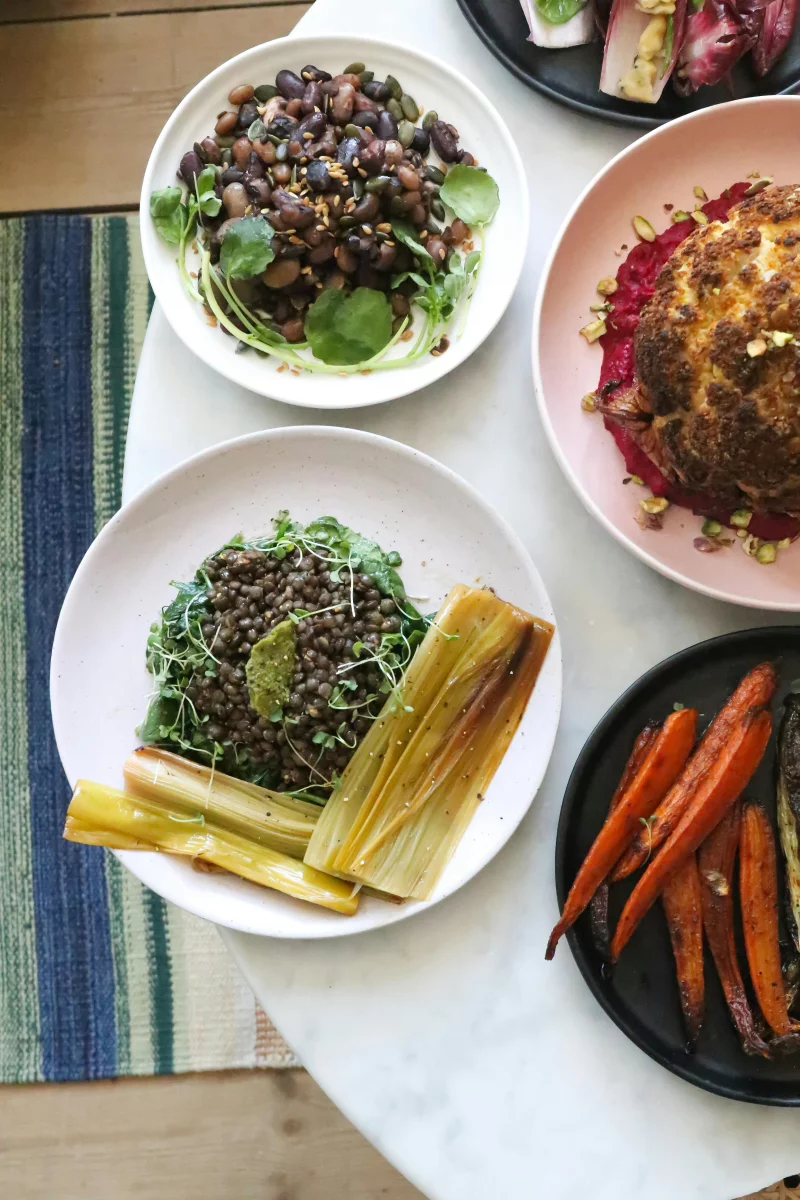 Top view ceramic plates with various healthy salads with green peas and beans served on table near grilled vegetables in restaurant