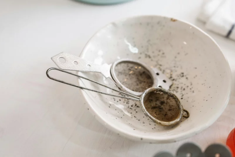 Detail of used kitchen sieve in a speckled ceramic bowl, conveying a rustic kitchen atmosphere.
