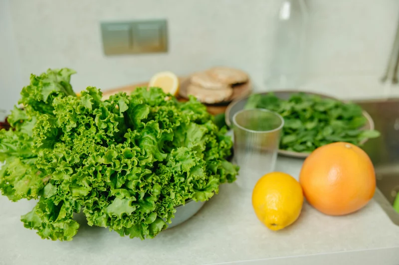 A vibrant display of fresh green lettuce and citrus fruits on a kitchen table.