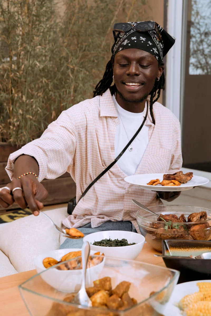A smiling man enjoys a delicious meal with a variety of dishes, creating a warm and inviting atmosphere.