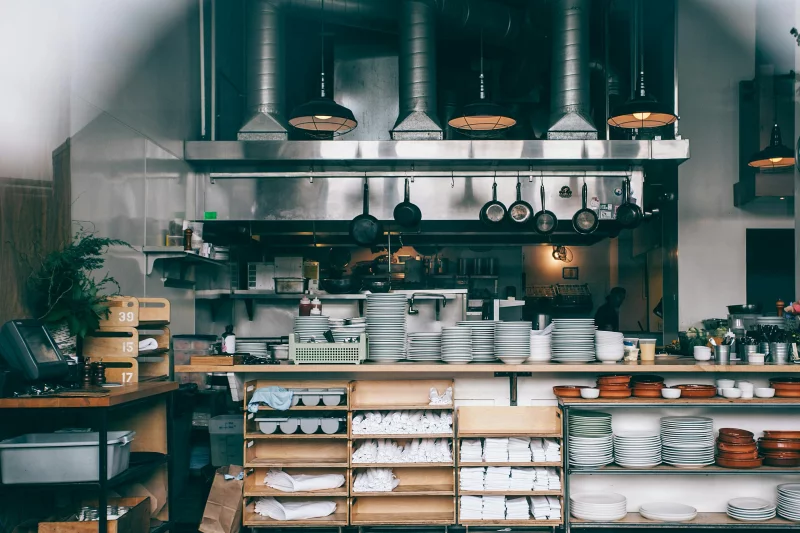 Interior of kitchen in modern restaurant with piles of plates and other different assorted utensils