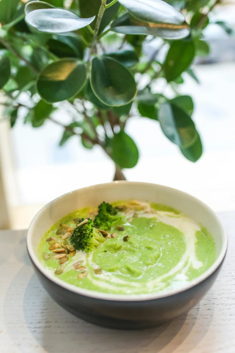 Delicious creamy broccoli soup garnished with seeds, a healthy meal option.