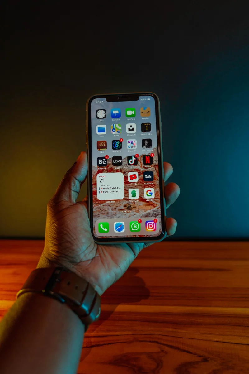 A hand holding a smartphone displaying app icons, with a modern minimalistic background.