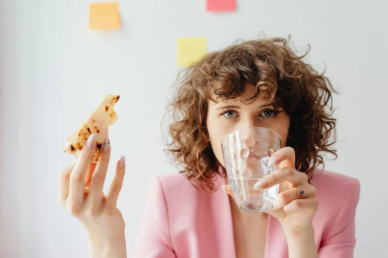 Businesswoman having a snack and water break in a home office setting. Vibrant, productive atmosphere.