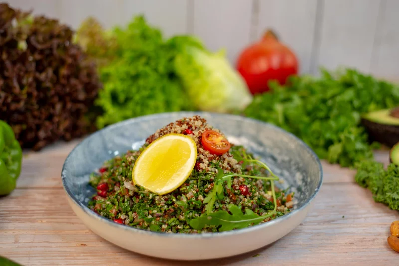 Vibrant quinoa salad with fresh herbs and lemon slice, garnished with cherry tomato.