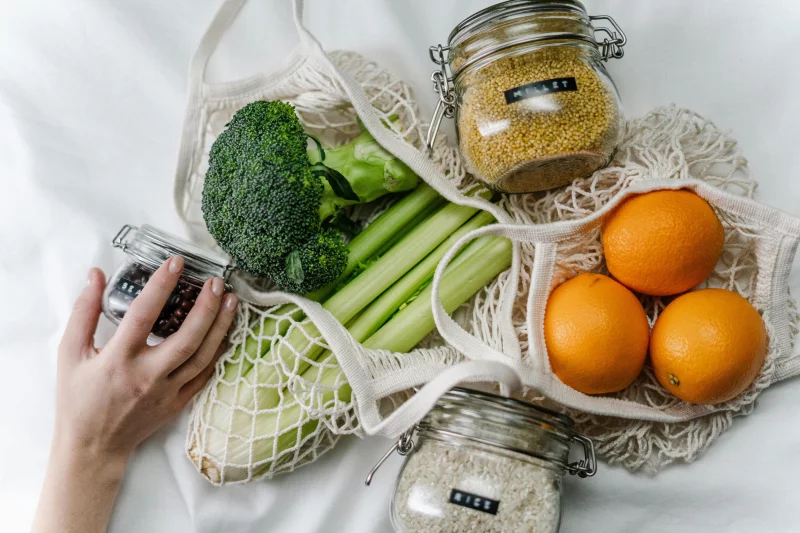 A flat lay of fresh vegetables and grains in reusable bags promoting zero waste and health.