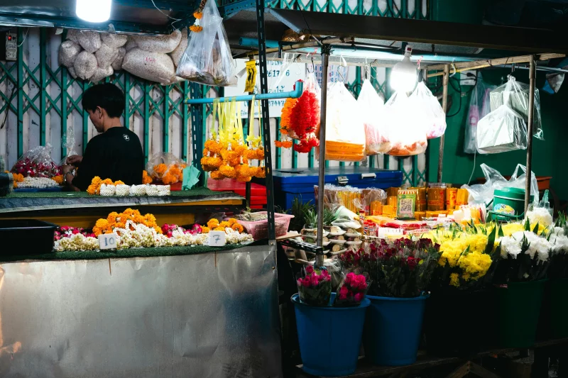 Colorful flower stall in a busy Bangkok night market showcasing fresh blooms and local produce.