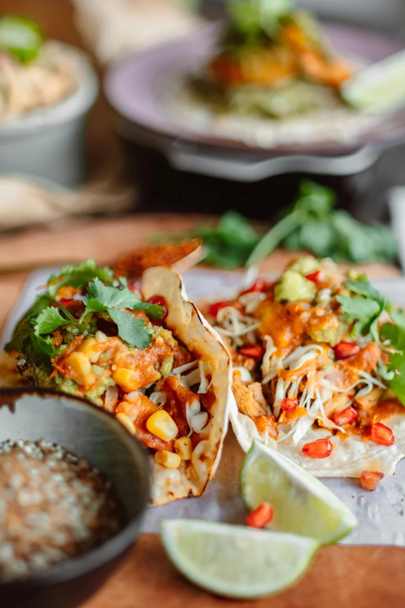 Close-up of fresh Mexican tacos with guacamole, lime, corn, and spices. A taste of vibrant Mexican cuisine.