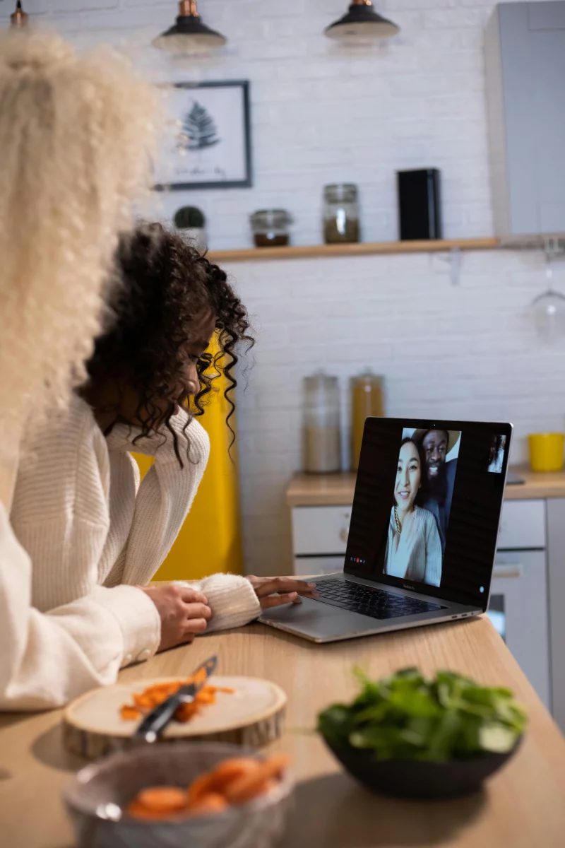 A woman and her daughter video chatting with loved ones in a modern kitchen.