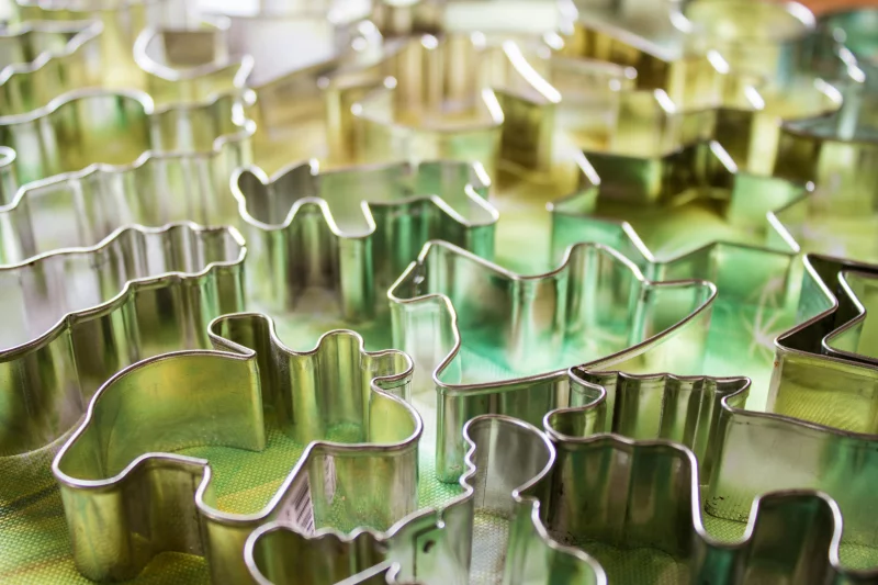 Close-up of diverse metal cookie cutters in abstract shapes on a colorful surface.