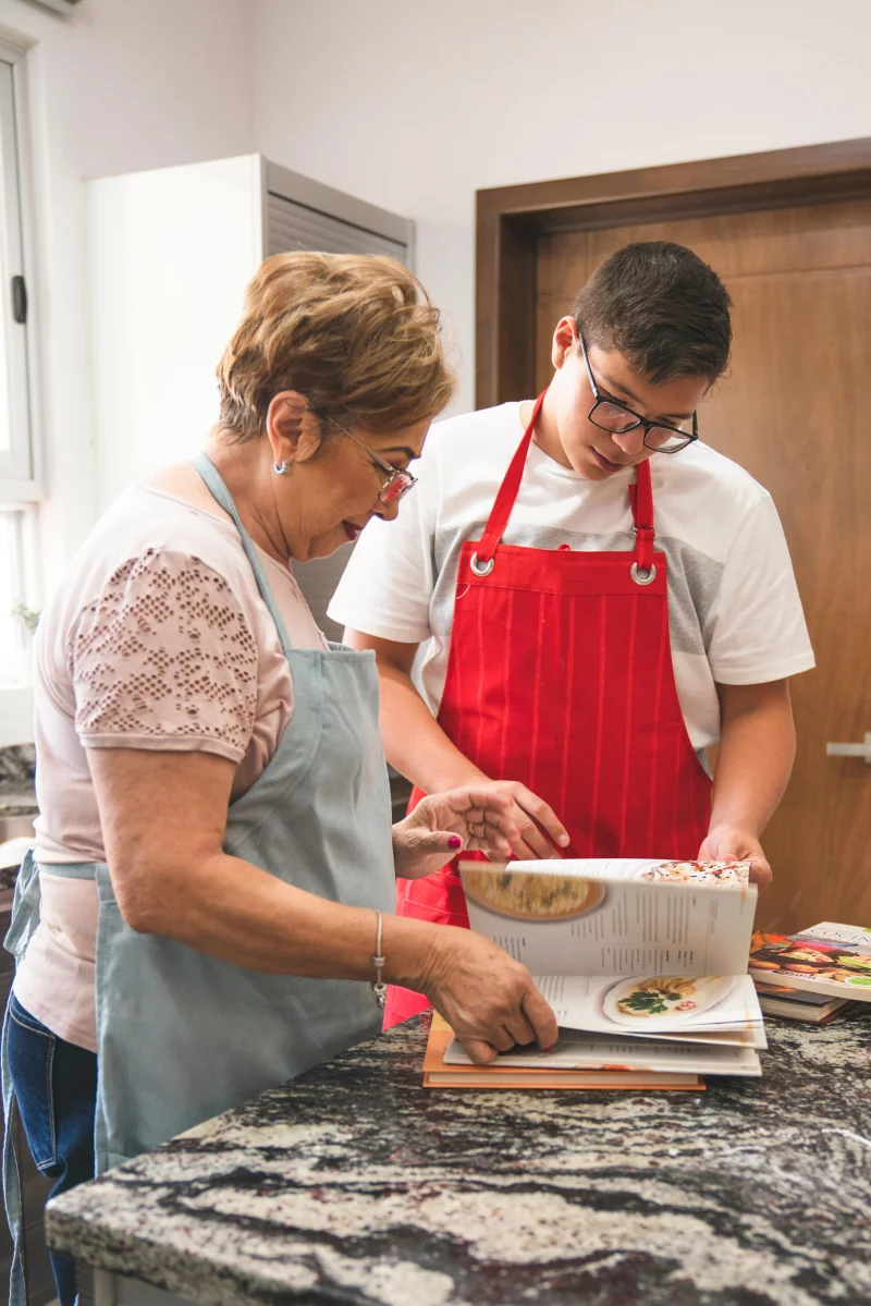A heartwarming scene of a grandmother and grandson exploring a recipe in their kitchen.