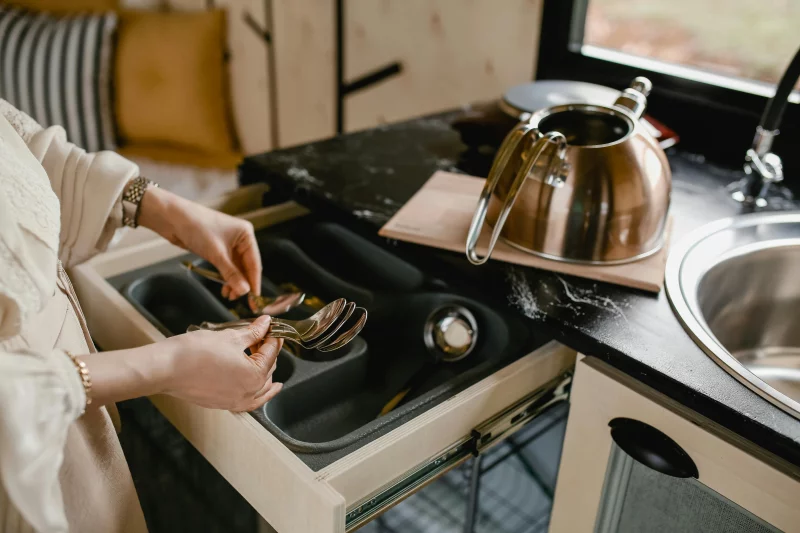 A person efficiently organizes silverware in a minimalist kitchen setting.