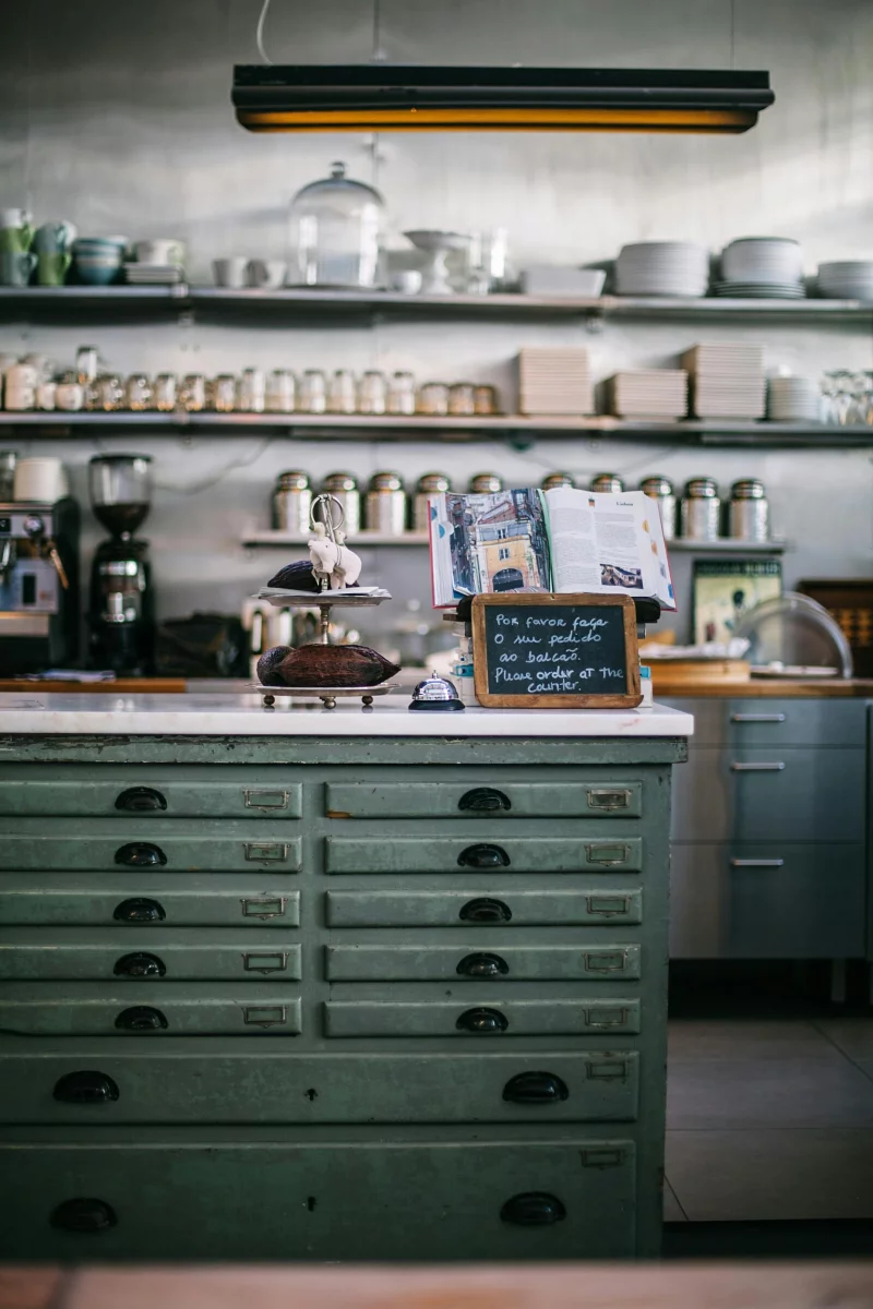 Cozy café interior featuring vintage green storage cabinets, jars, and kitchenware.
