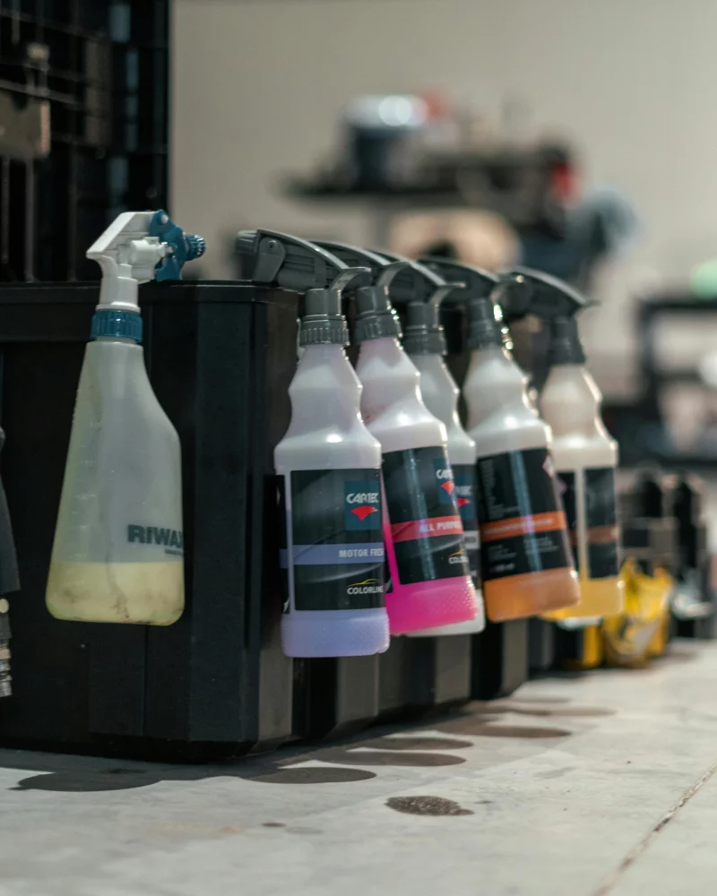 Close-up of various car care spray bottles lined up in a workshop.