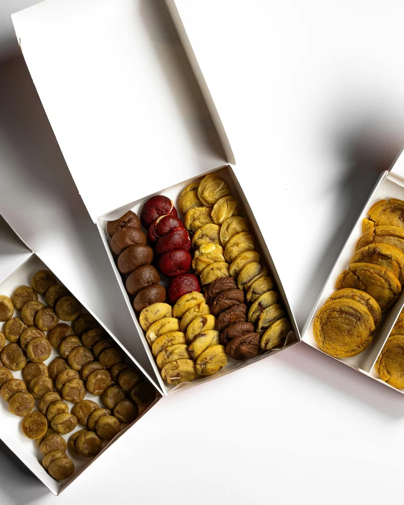 Top view of various cookies arranged in open boxes on a white background. Perfect for food photography lovers.