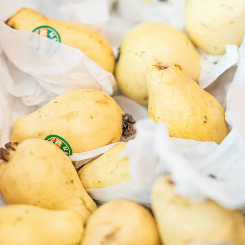 Close-up of fresh yellow pears in paper wrap, highlighting their healthy appeal.