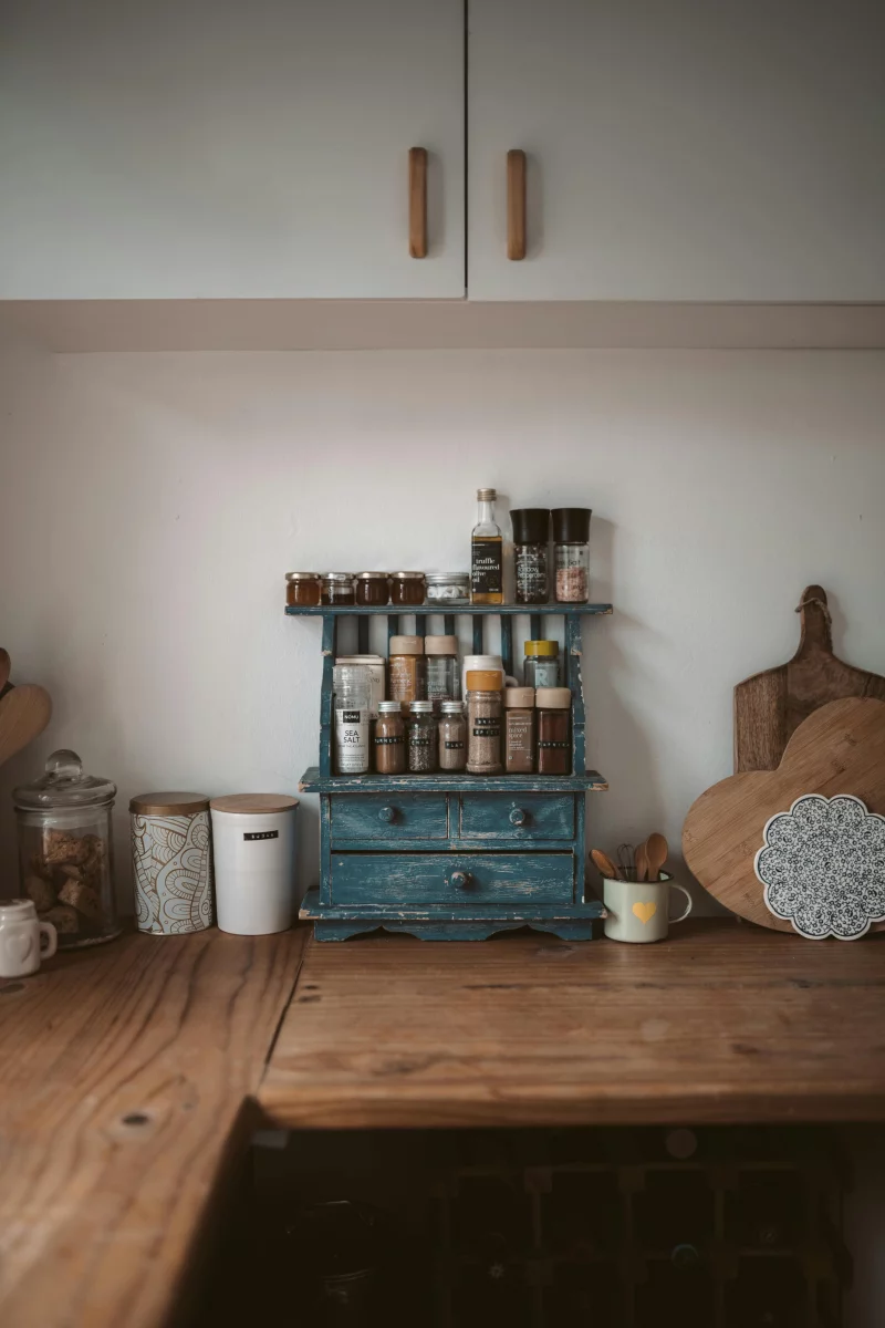 Rustic wooden countertop with neatly organized spice rack in home kitchen.