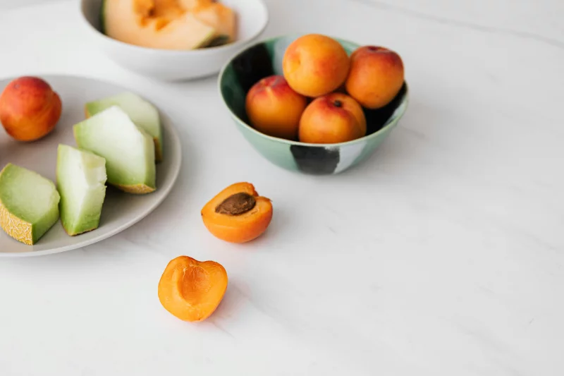 From above of ripe fruits in plate and bowls placed on white marble table