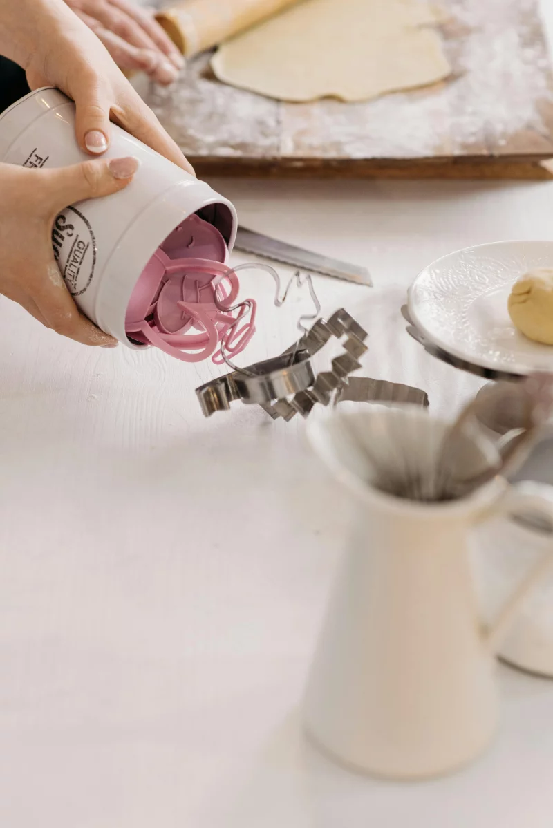 Culinary scene with hands organizing baking tools on a clean kitchen counter.