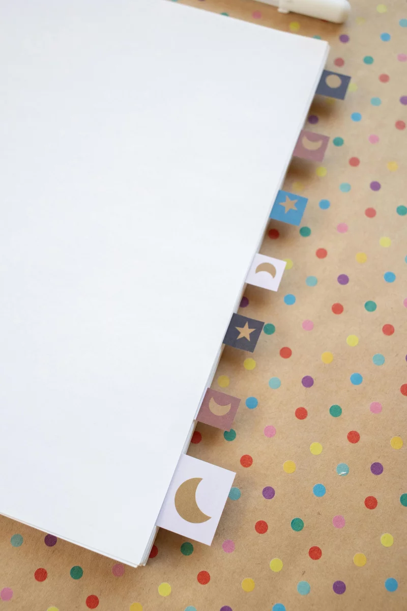 A polka dot designed notebook featuring moon and star tabs on a vibrant background.