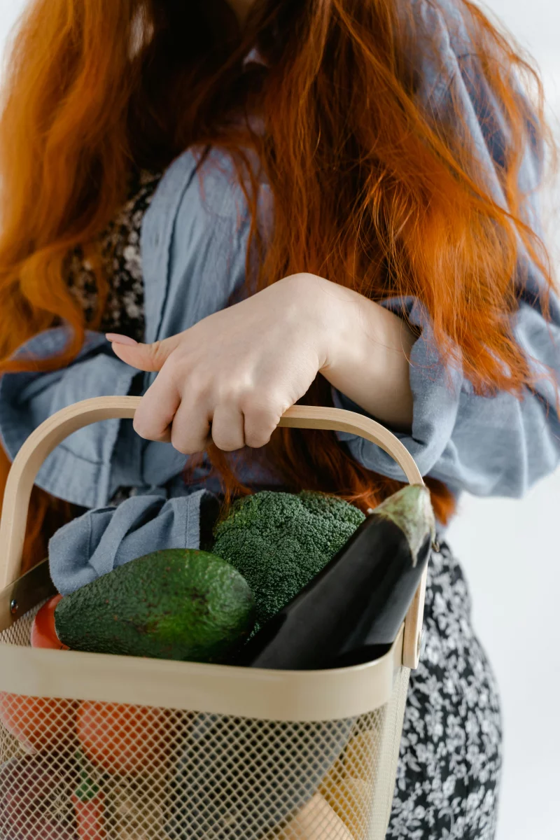 Close-up of a woman holding a basket filled with fresh vegetables. Perfect for themes of health and organic living.