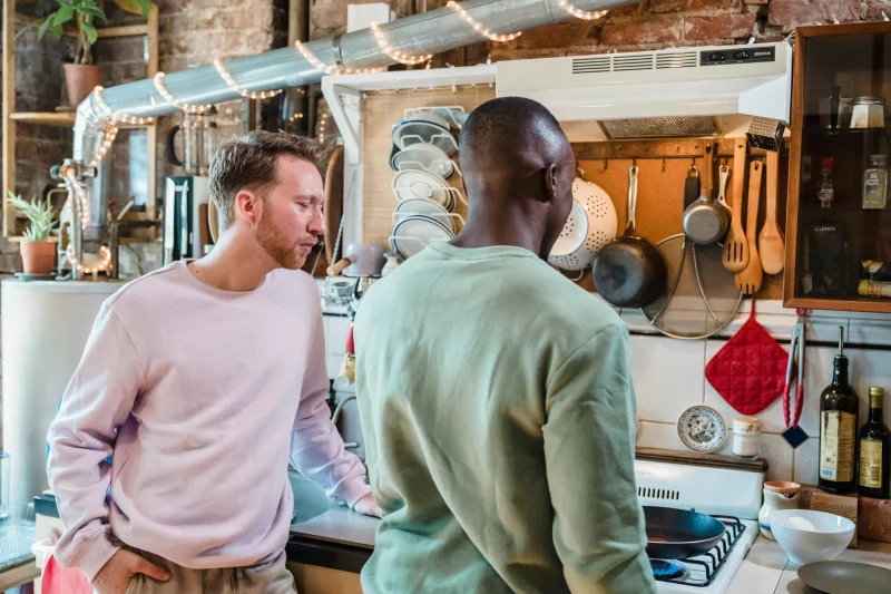Two men cooking in a stylish, rustic kitchen, enjoying a shared moment.