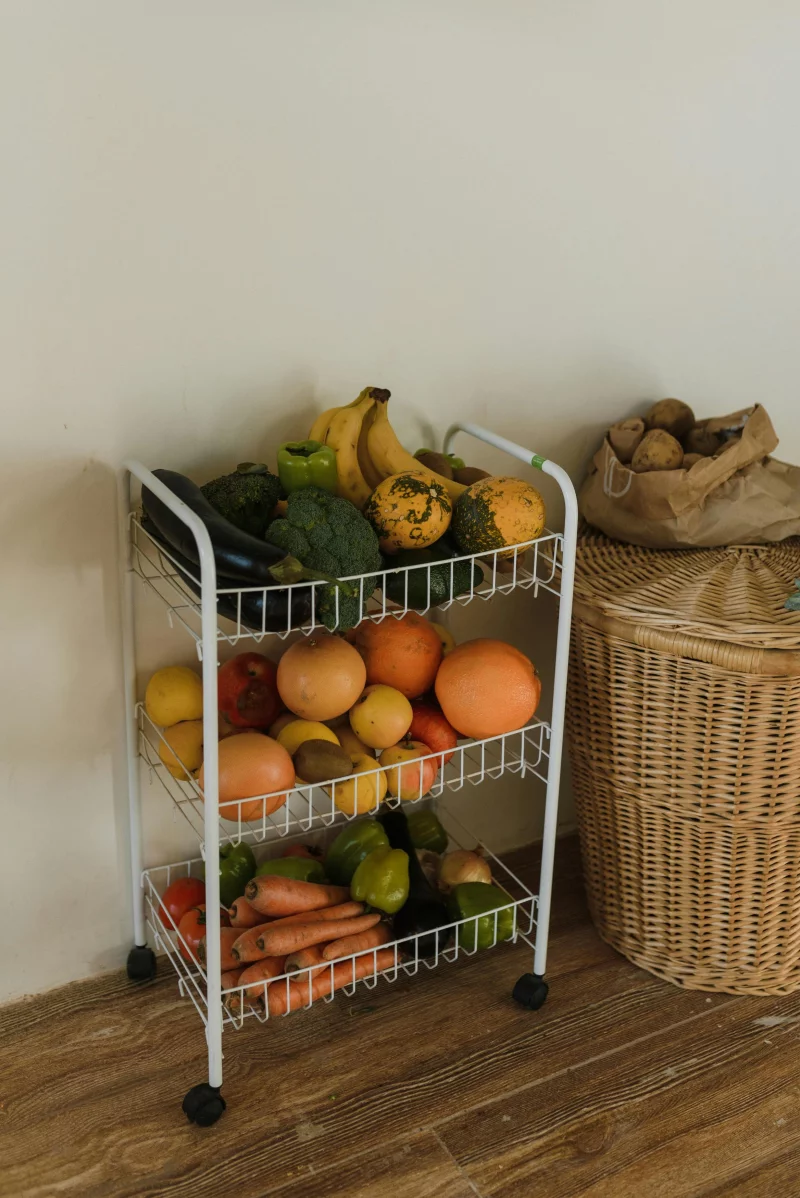Wire rack with assorted fresh fruits and vegetables in a cozy indoor setting.