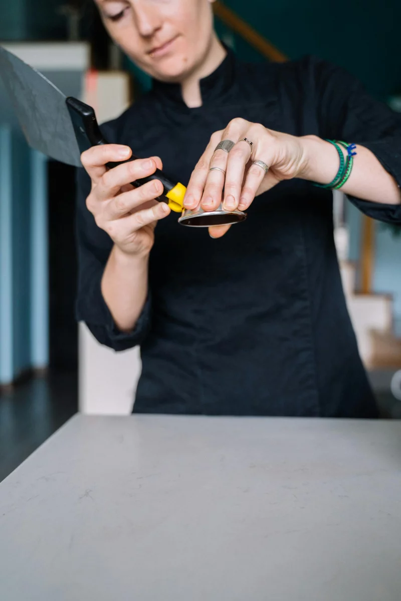 Close-up of chef's hands preparing a tool in a professional kitchen.