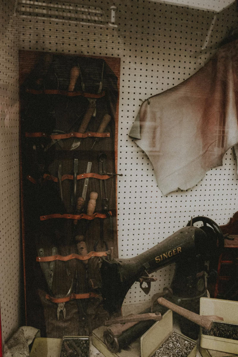 A vintage workshop showcasing a Singer sewing machine surrounded by various artisan tools and fabric.