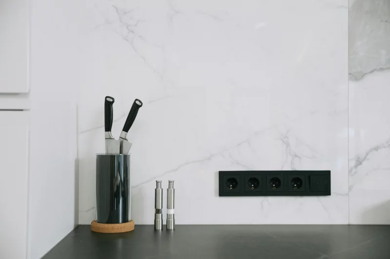 Modern kitchen with marble backsplash, knife holder, and power outlets.