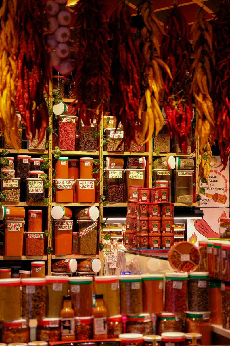 A vibrant vertical display of spices in jars at a market store.