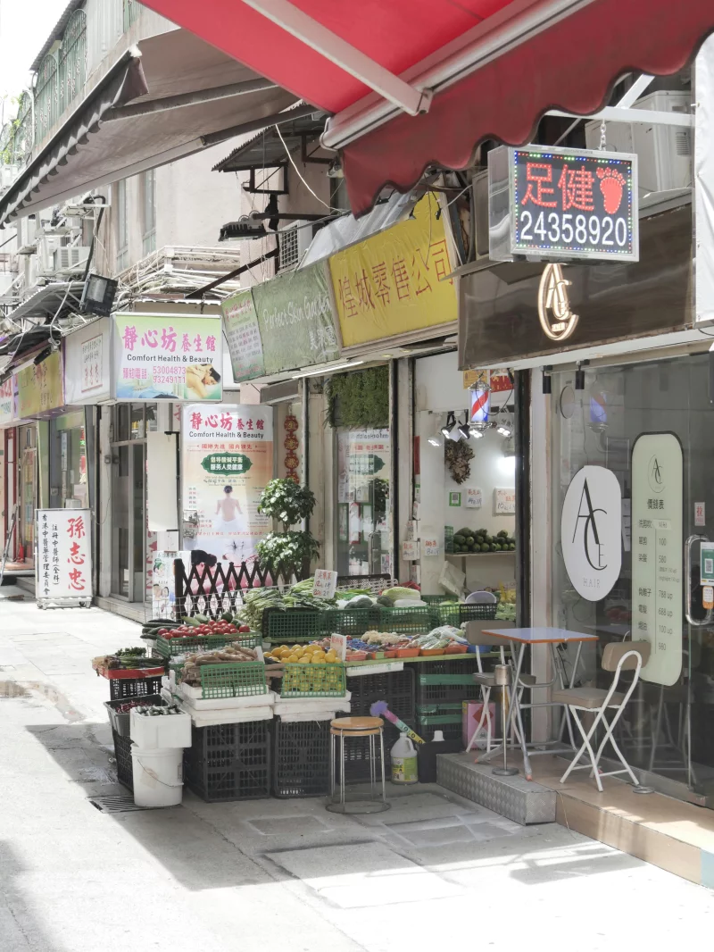 A vibrant street market with fresh produce and storefronts on a sunny day.