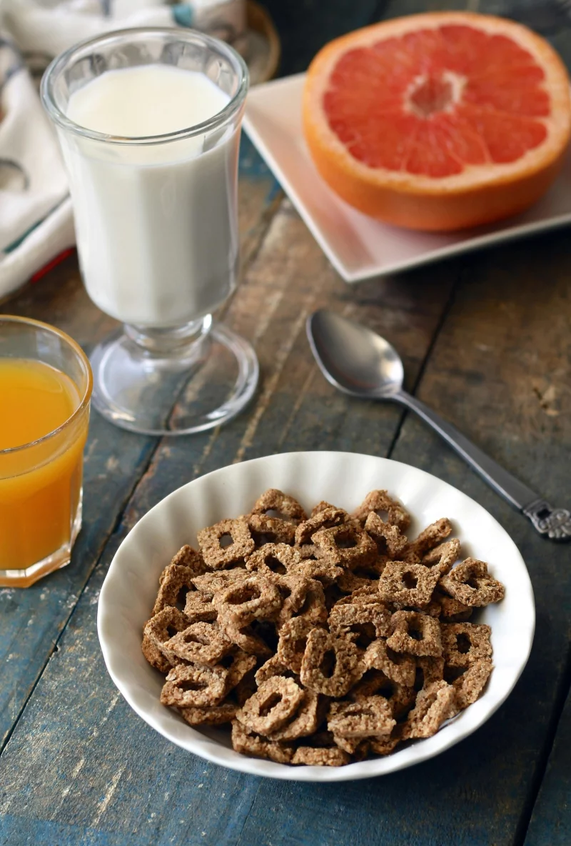 Image of a healthy breakfast with cereal, grapefruit, juice, and milk on a table.