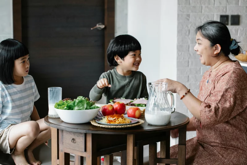 A joyful family breakfast scene with children and grandmother sharing healthy food.