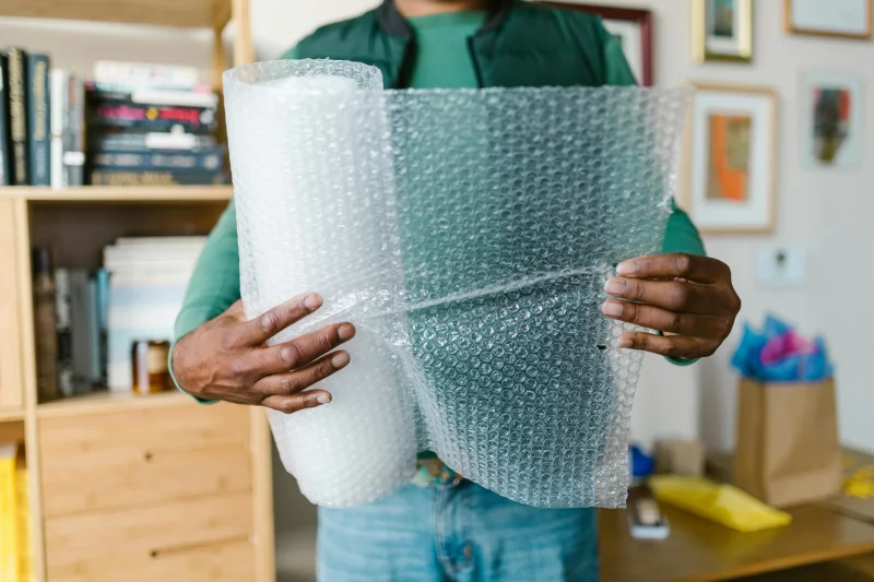 Close-up of hands holding bubble wrap at home. Ideal for packing or moving themes.