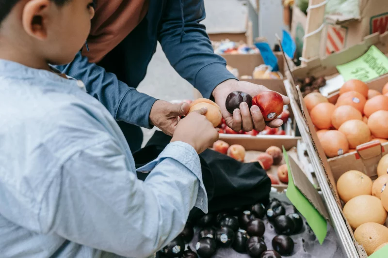 Father and son choosing fresh fruits together at a local market stand.