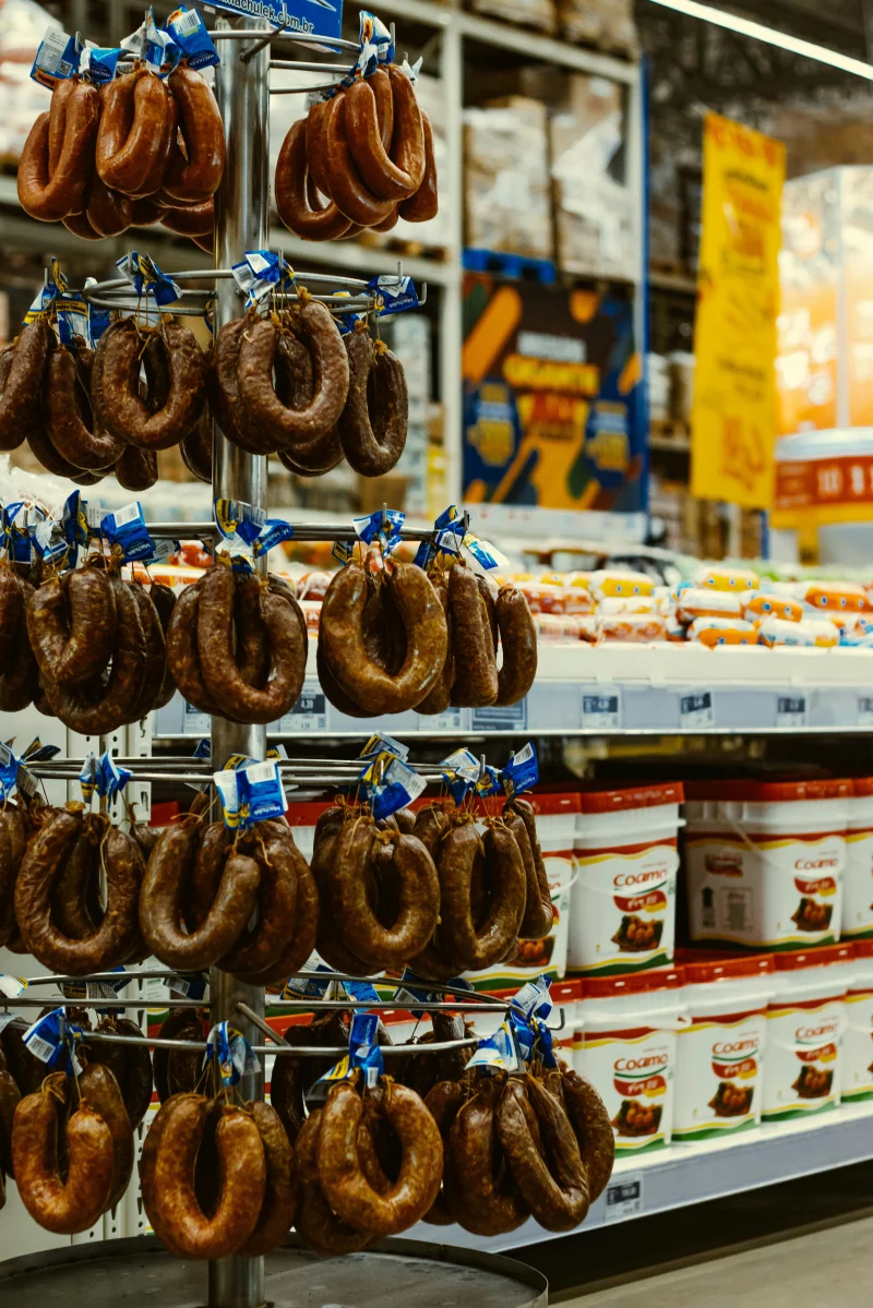 A vertical shot of various sausages on a stainless steel stand in a Brazilian supermarket.