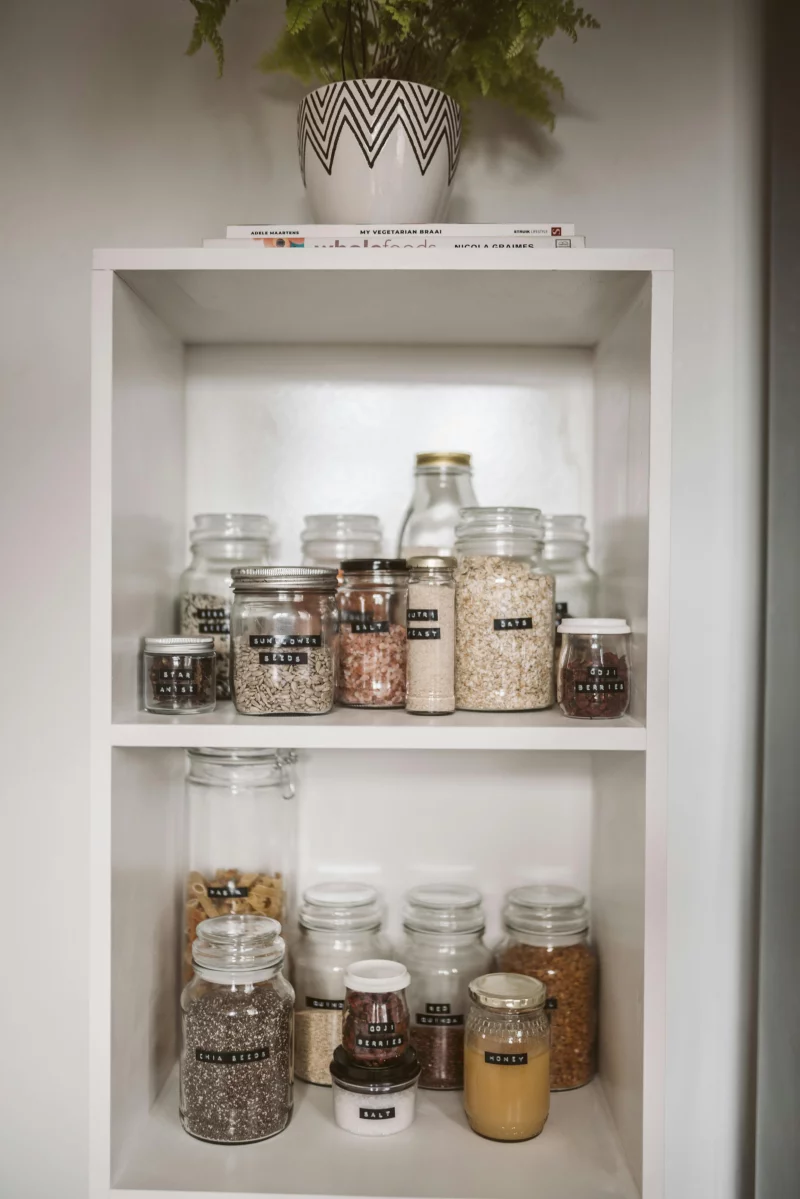 Neatly arranged pantry showcasing labeled glass jars with assorted grains and seeds.