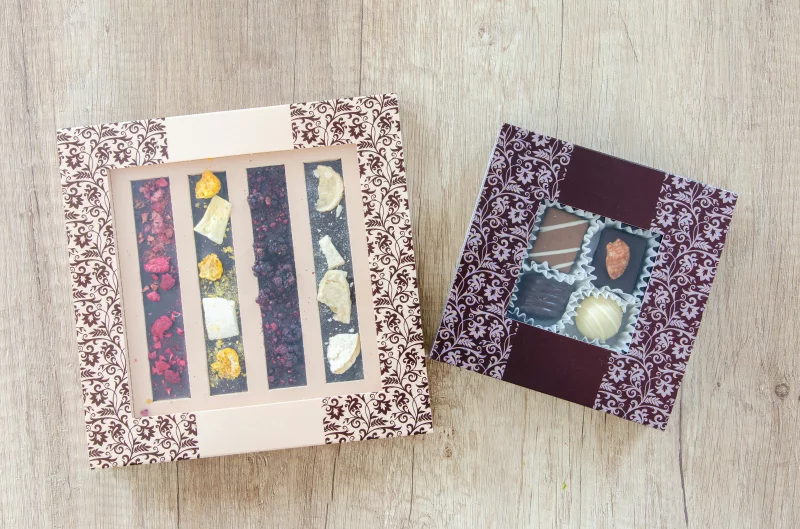 Top view of assorted chocolate gift boxes with elegant designs on a wooden table, perfect for gifting or special occasions.