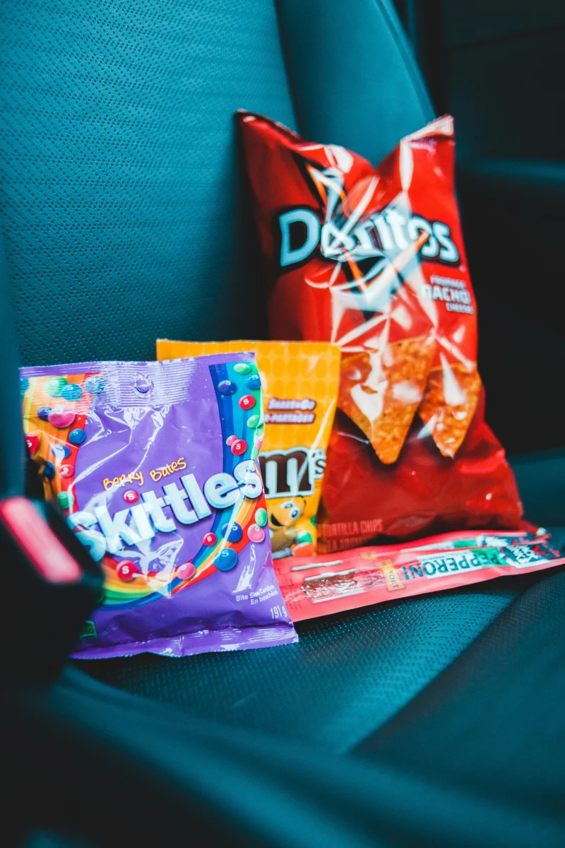 Colorful packages with interesting design of different delicious snacks placed on modern car seat in daylight