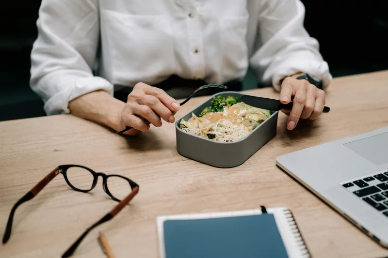 Adult enjoying a healthy meal at the office desk during lunch break.