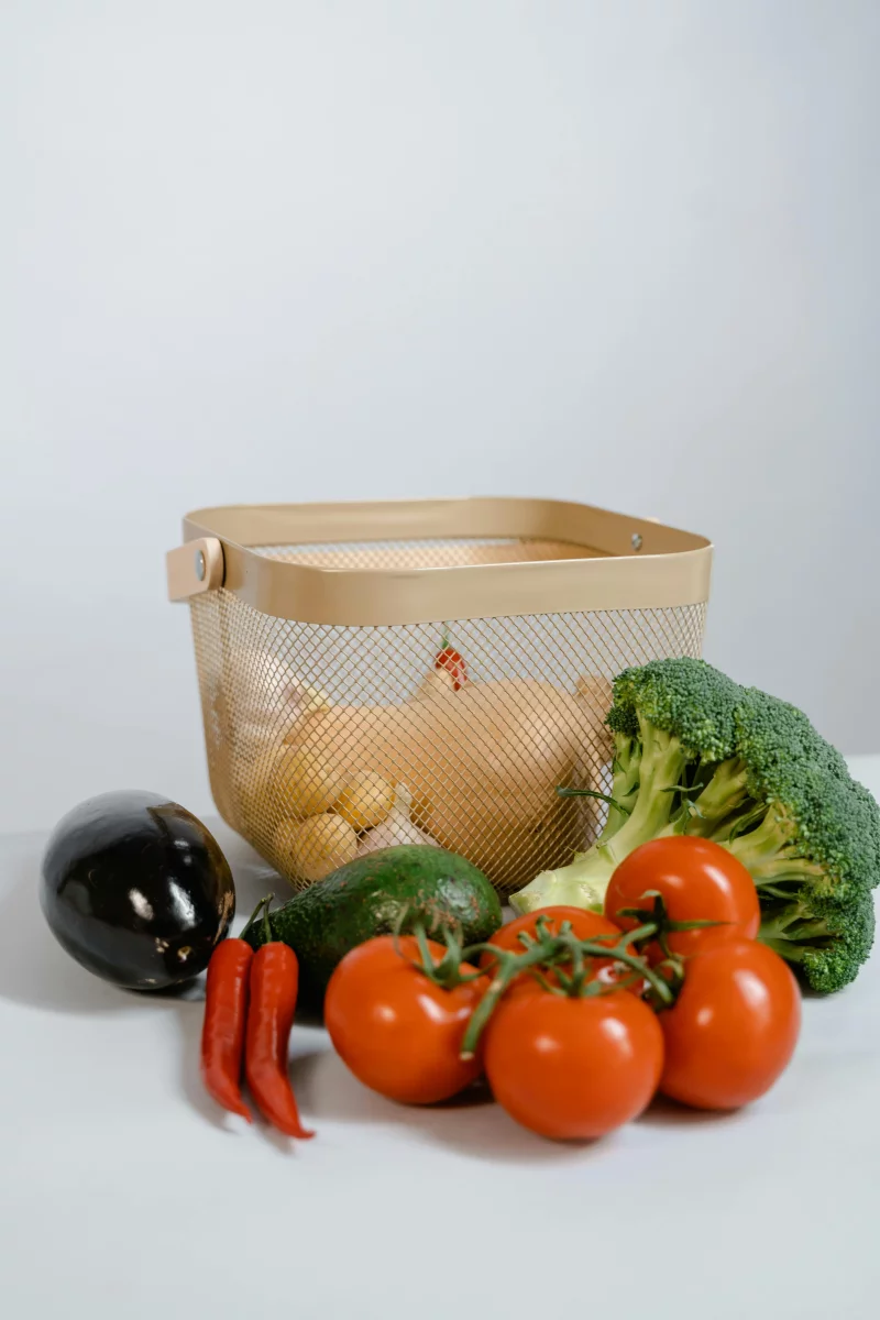 A variety of fresh vegetables including tomatoes, broccoli, and chilies in a basket.