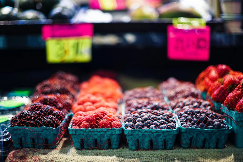 Close-up of fresh berries in colorful containers at a vibrant farmers market.