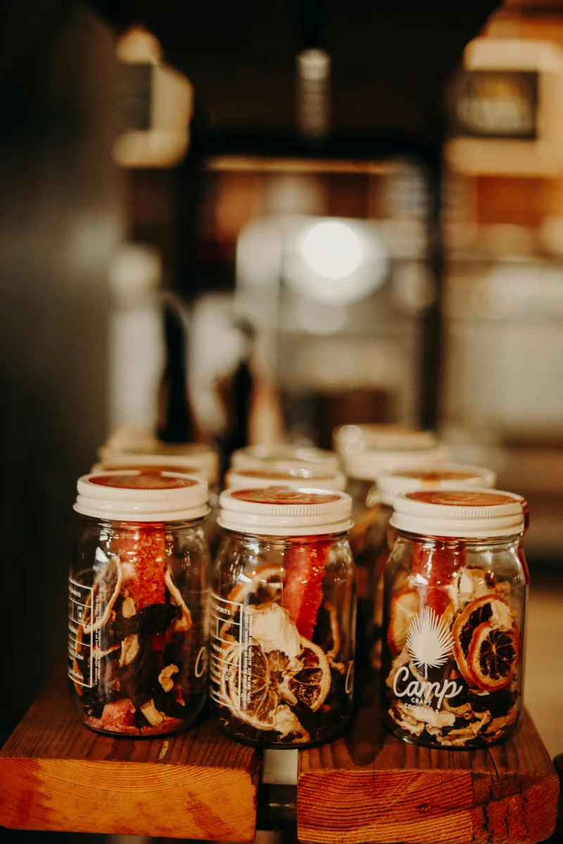 Many glass jars with assorted dried fruits placed on shelf in modern cafeteria